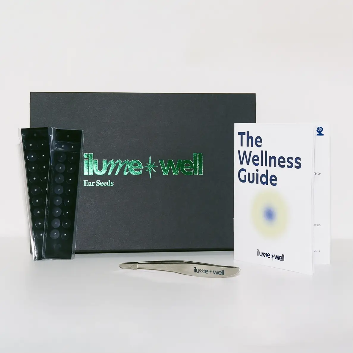 ilumewell product set with ear seeds, tweezers, and wellness guide on a white background