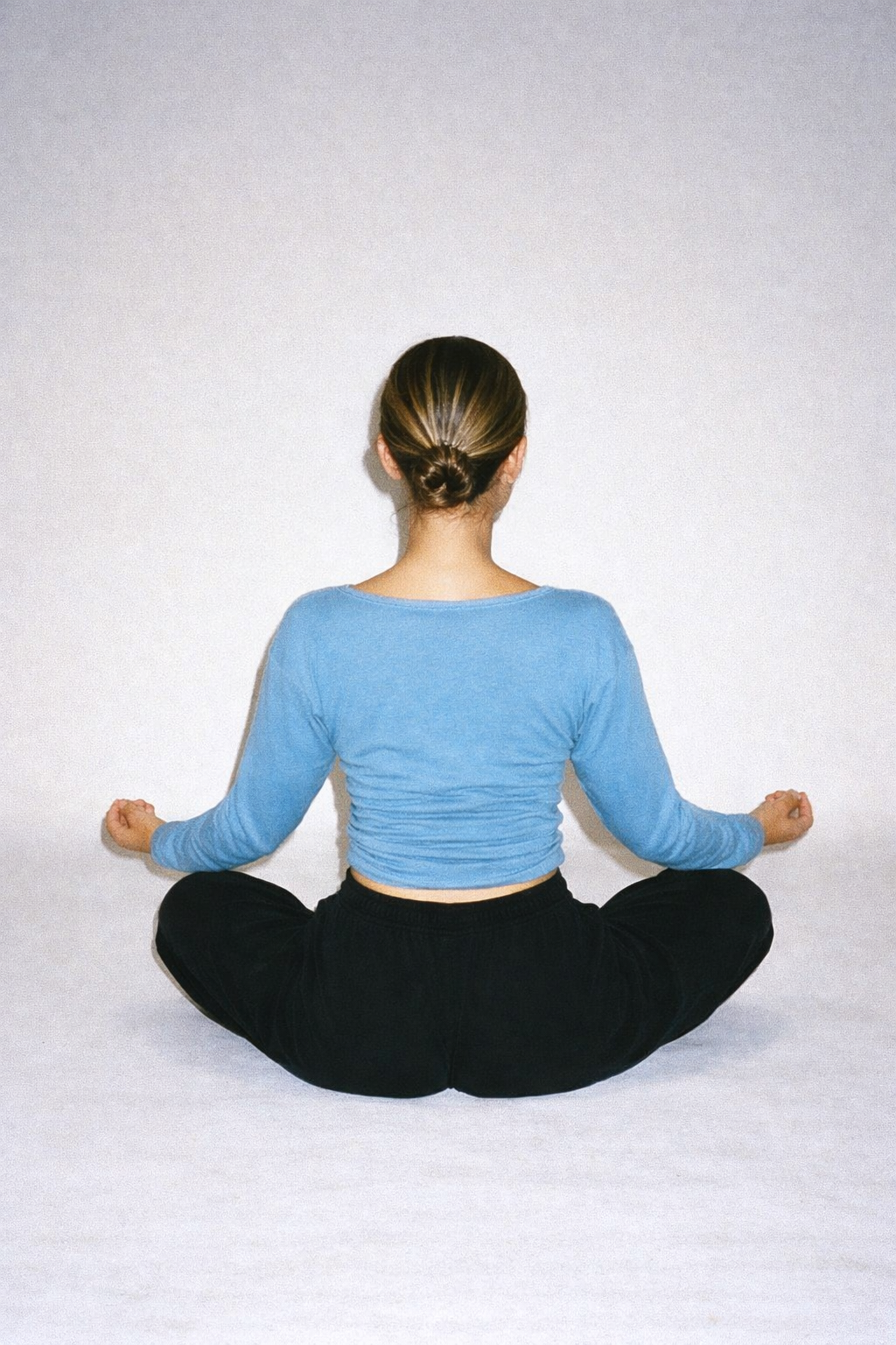 Person sitting in a yoga pose on a white background