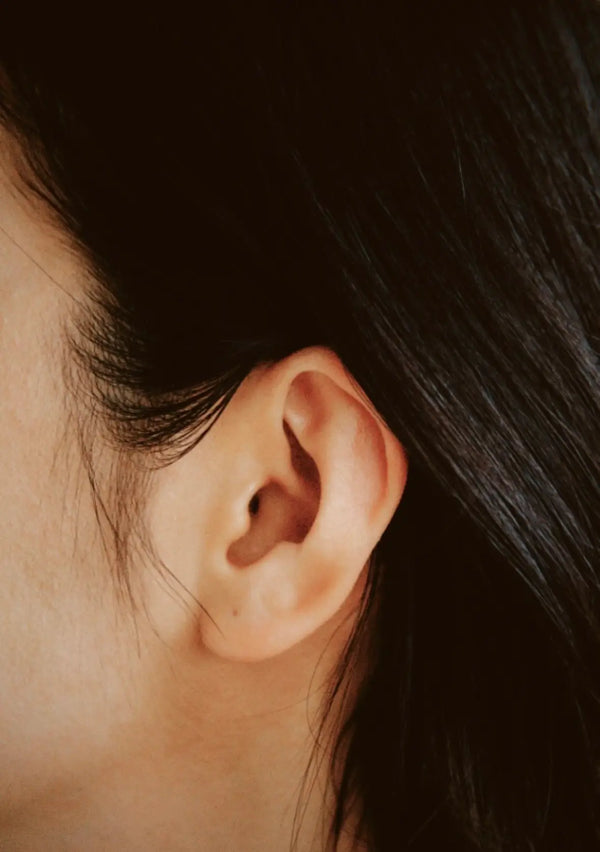 Close-up of a person's ear with dark hair partially covering it