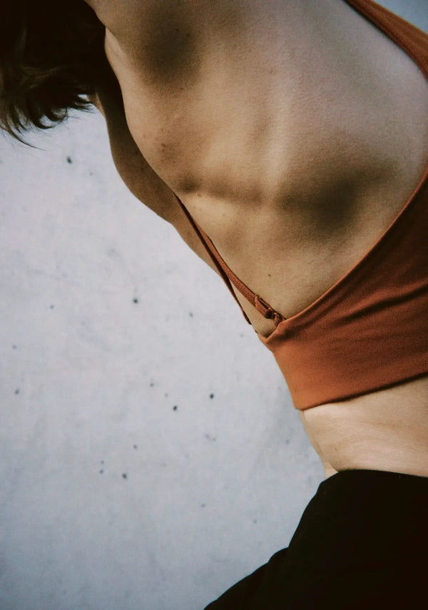 Person wearing a rust-colored top on a light gray background